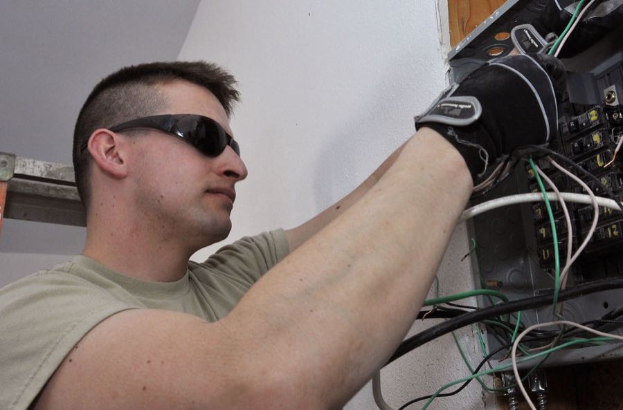 An electrician wiring a breaker panel (openly-licensed stand-in photo)